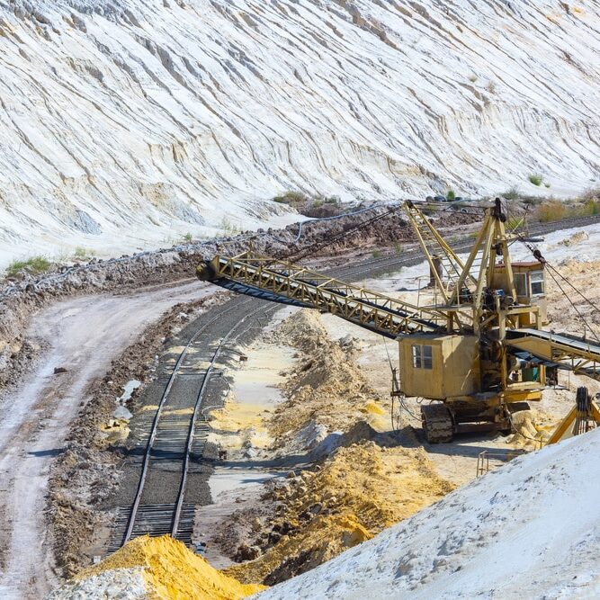 Quarry extraction porcelain clay(kaolin) and quartz sand in the open pit mine. Powerful industrial belt conveyor loader near the access railway track at the deposit openin